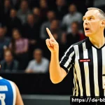 Home 20 농구 심판이 보는 경기 룰 - A dynamic basketball referee in mid-action on a professional indoor court in Germany, wearing a mode...